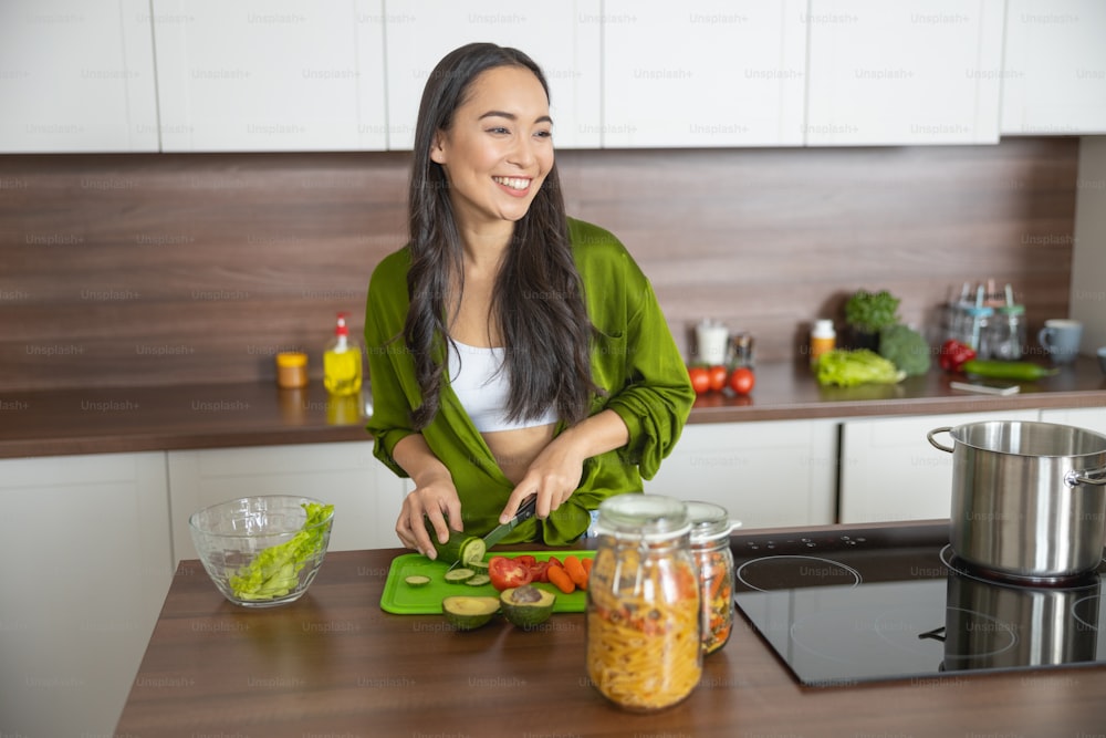 Dona de casa moderna feliz fazendo uma salada com ingredientes saudáveis