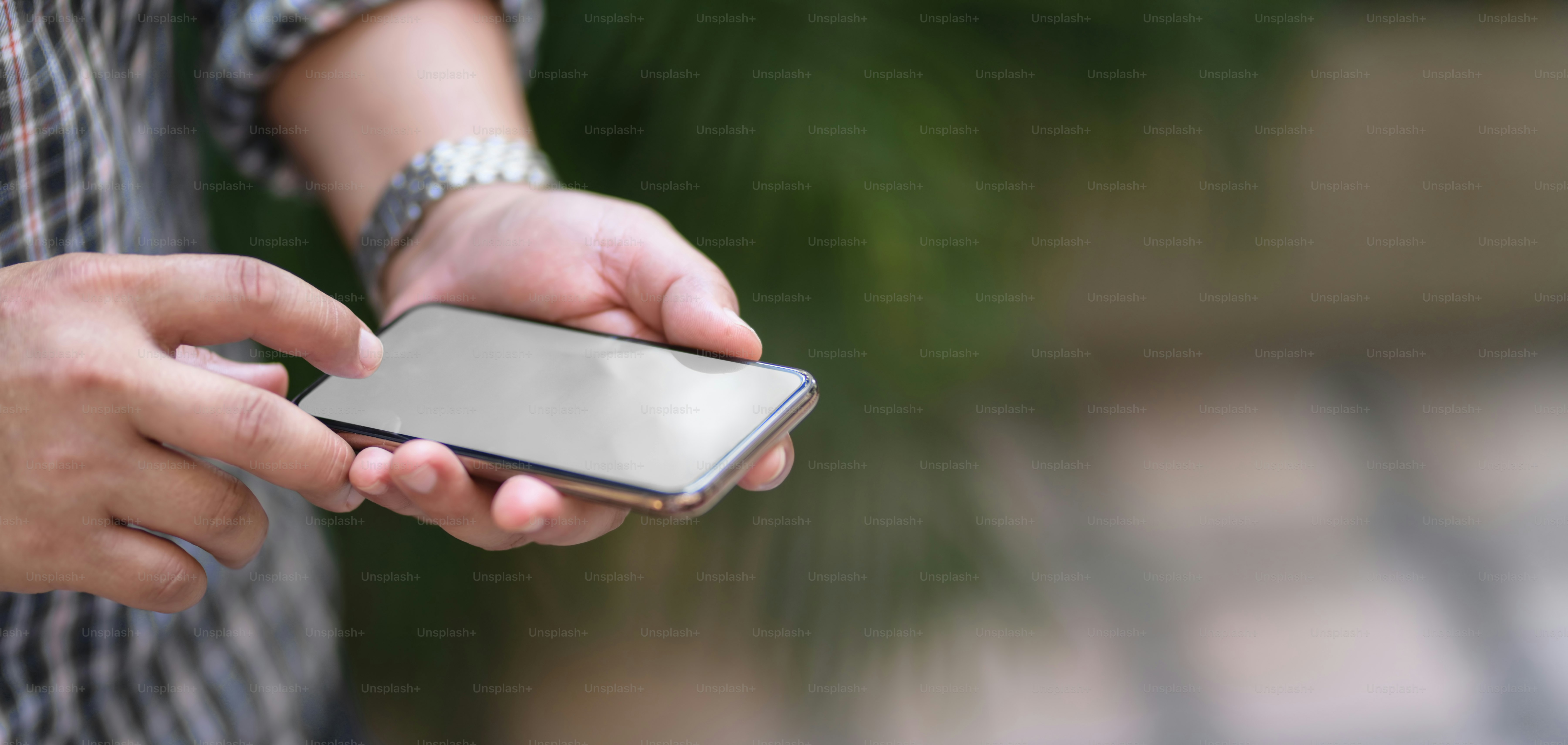Close-up view of young professional businessman using mock up smartphone with outdoor office background