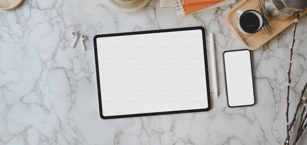 Tiro cenital de un espacio de trabajo elegante con tableta y teléfono inteligente de pantalla en blanco con suministros de oficina sobre fondo de escritorio de mármol