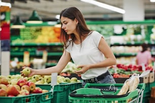 Vegetables and fruits. Female shopper in casual clothes in market looking for products.