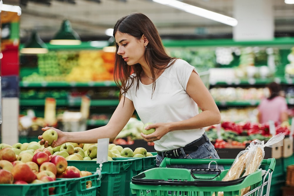 Vegetables and fruits. Female shopper in casual clothes in market looking for products.