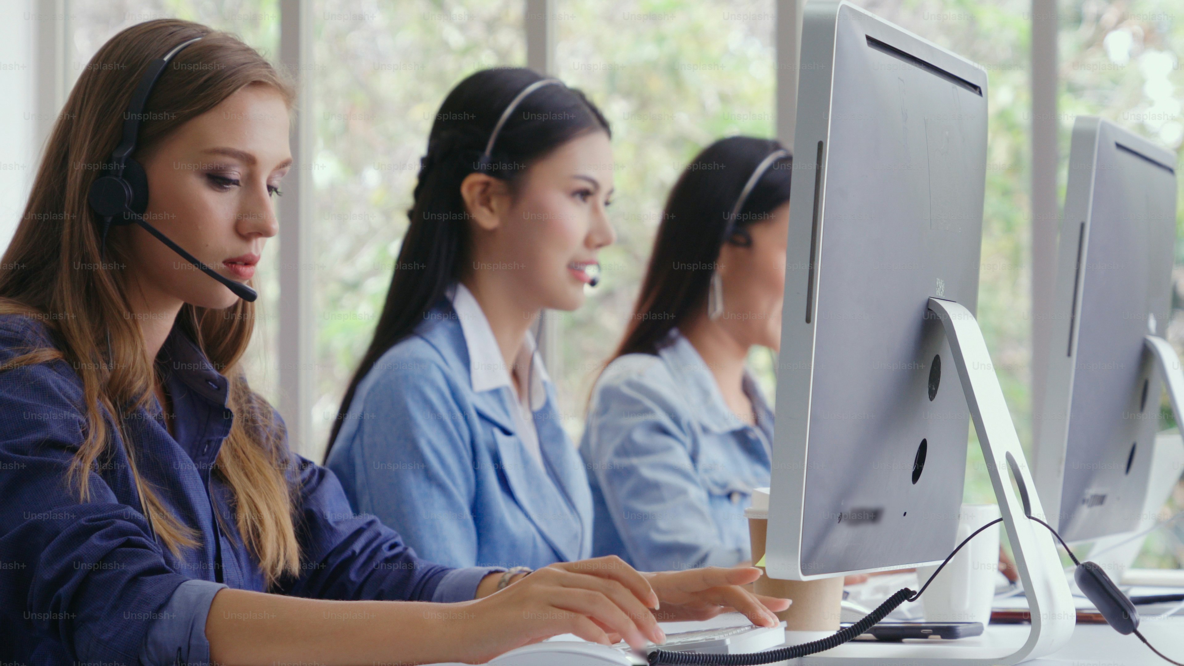 Customer support agent or call center with headset works on desktop computer while supporting the customer on phone call. Operator service business representative concept.