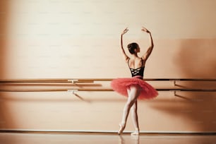 Back view of graceful ballet dancer rehearsing at ballet studio. Copy space.