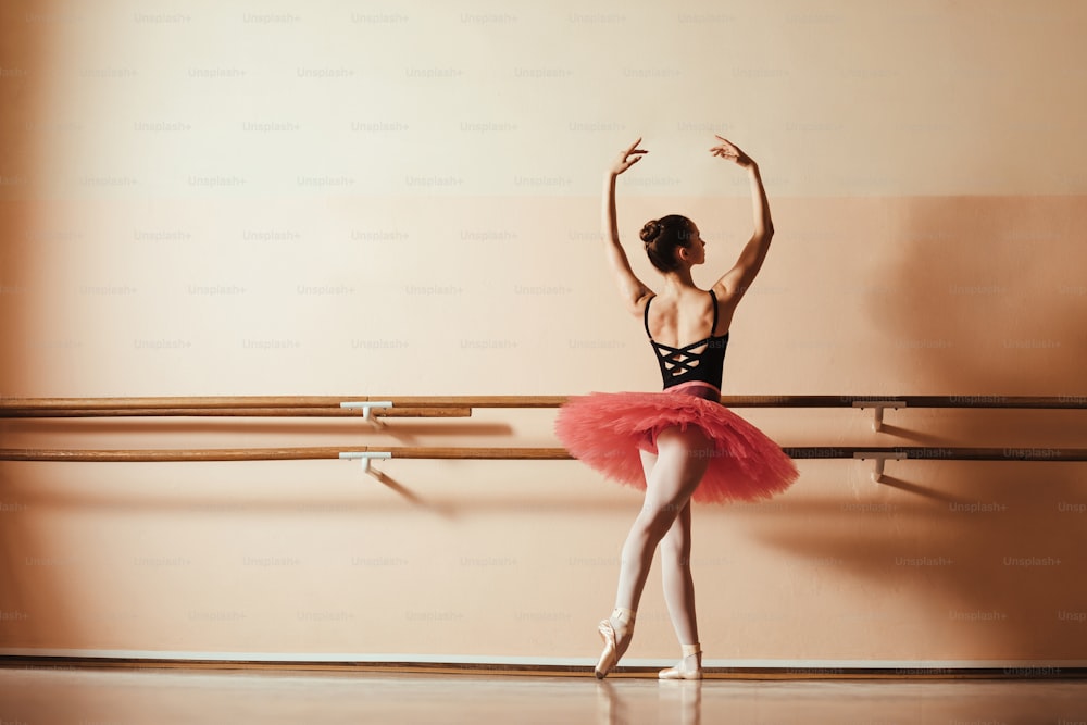 Vista trasera de una elegante bailarina de ballet ensayando en un estudio de ballet. Espacio de copia.