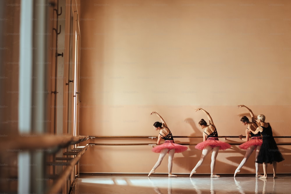 Vista trasera de bailarinas de ballet teniendo una clase con un profesor de ballet en el estudio de danza. Espacio de copia.