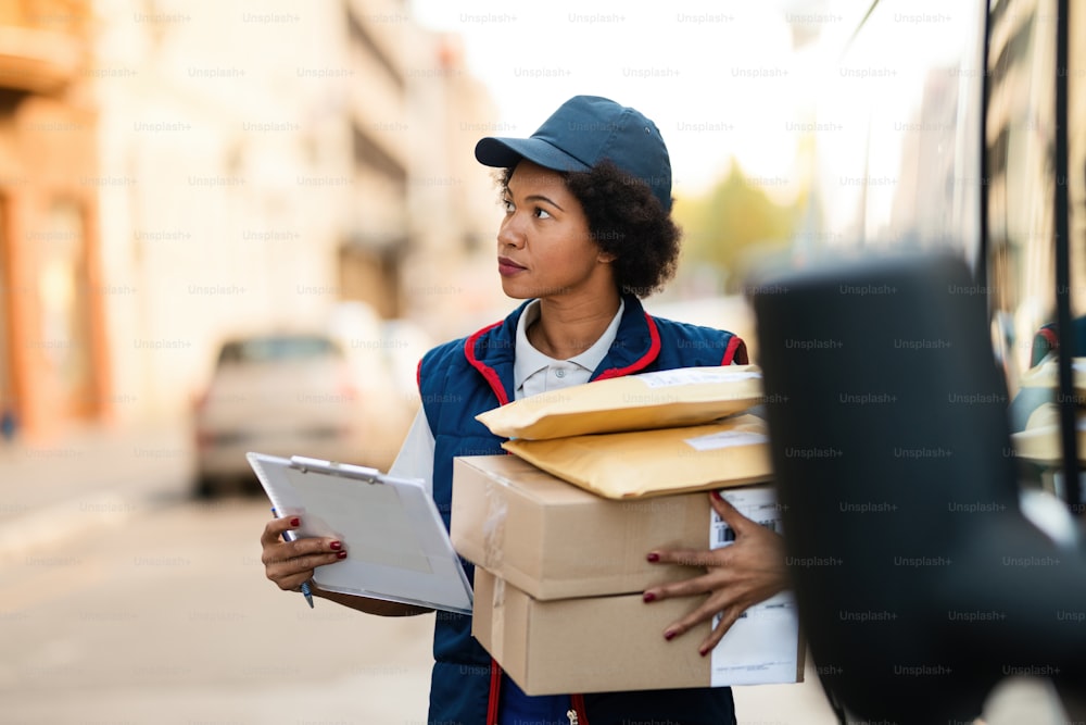 Black female courier carrying packages for delivery in the city.