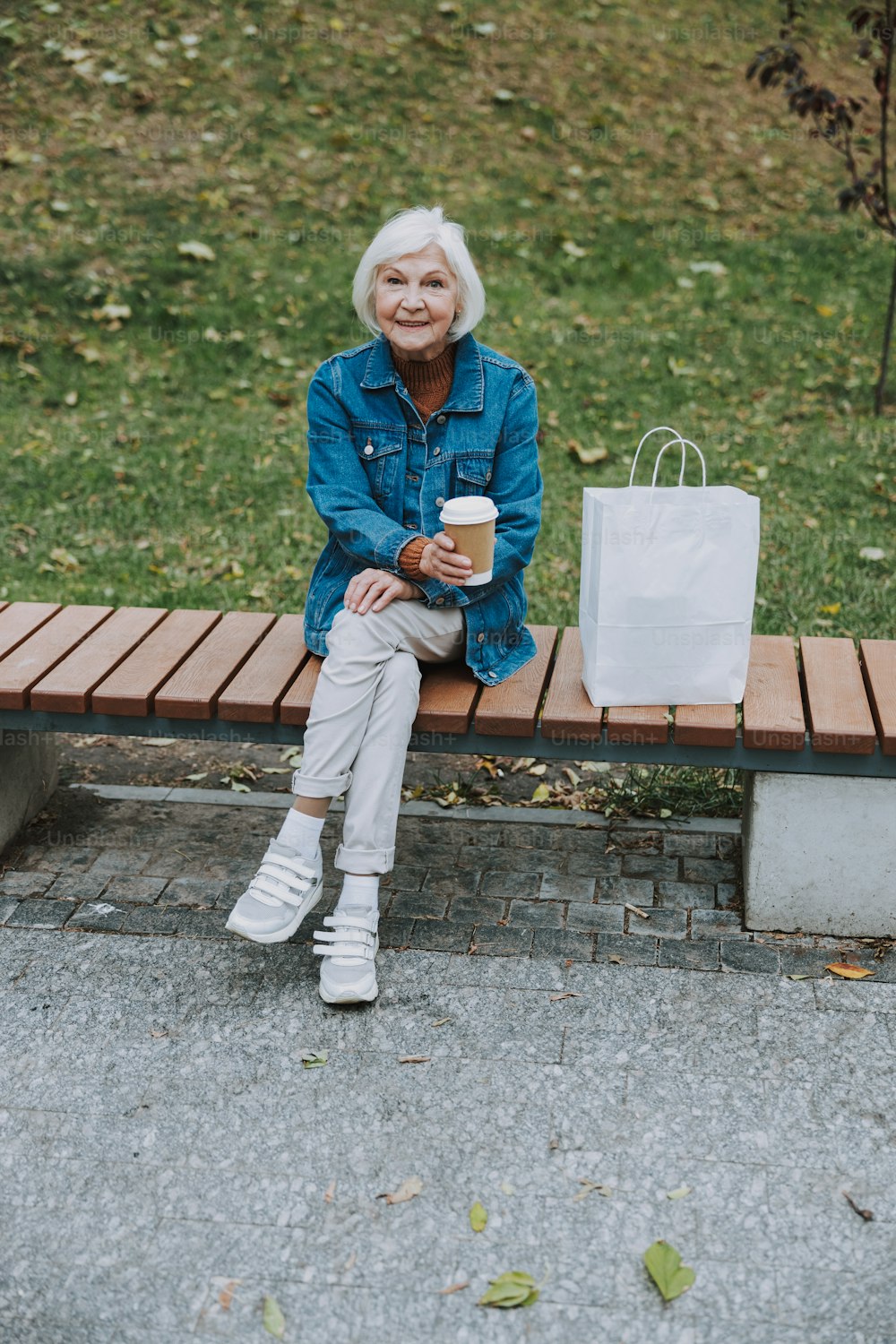 Lächelnde Frau in Jeansjacke mit heißem Getränke-Stockfoto
