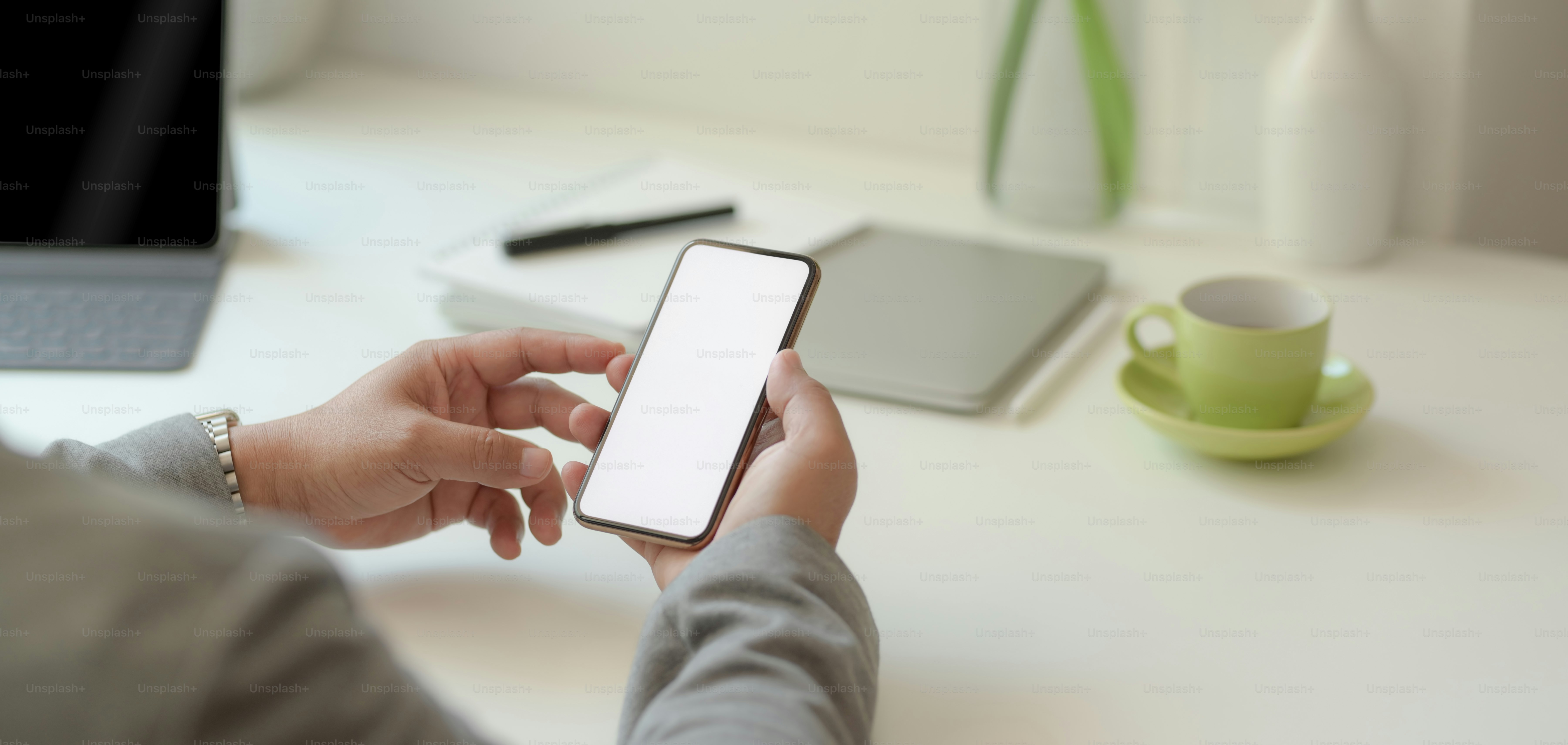 Close-up view of professional businessman holding blank screen smartphone in his comfortable office room