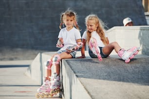 On the ramp for extreme sports. Two little girls with roller skates outdoors have fun.