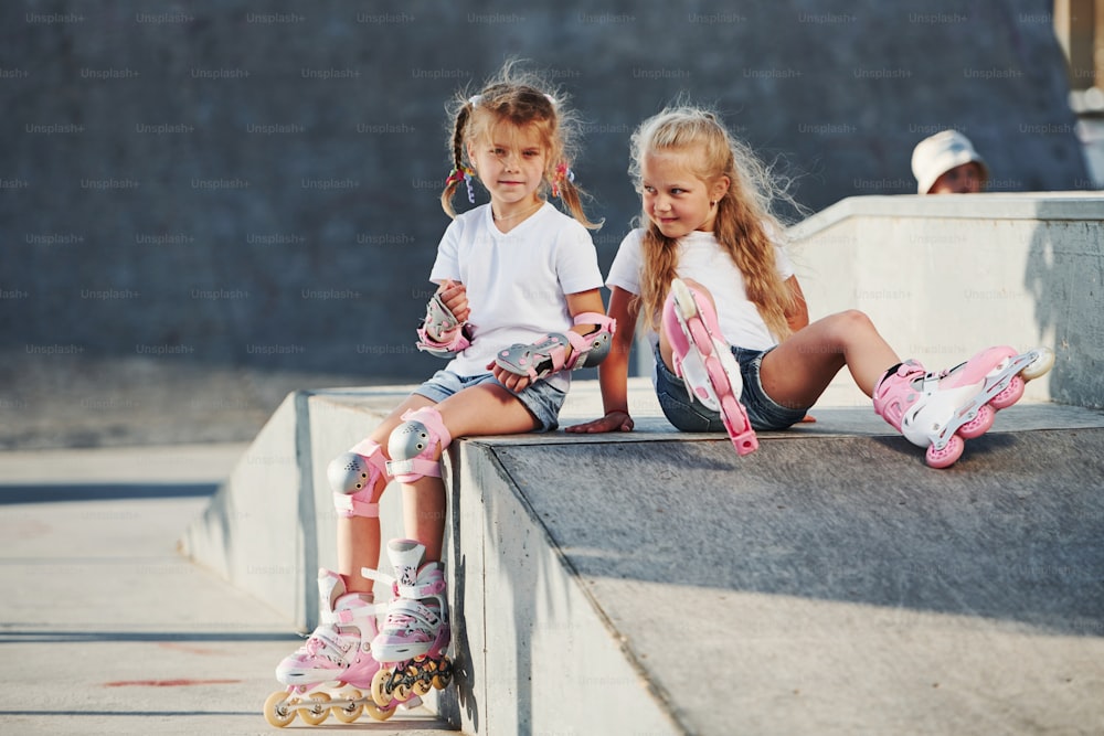 On the ramp for extreme sports. Two little girls with roller skates outdoors have fun.