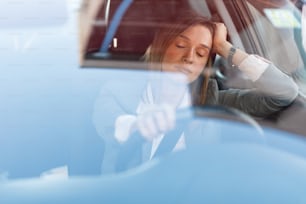 Müde Geschäftsfrau, die sich mit geschlossenen Augen ausruht, ein Auto fährt und im Stau steht.
