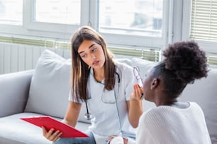 Doctor comforting her depressed patient. medicine, healthcare and people concept - doctor with clipboard and sad woman patient at hospital