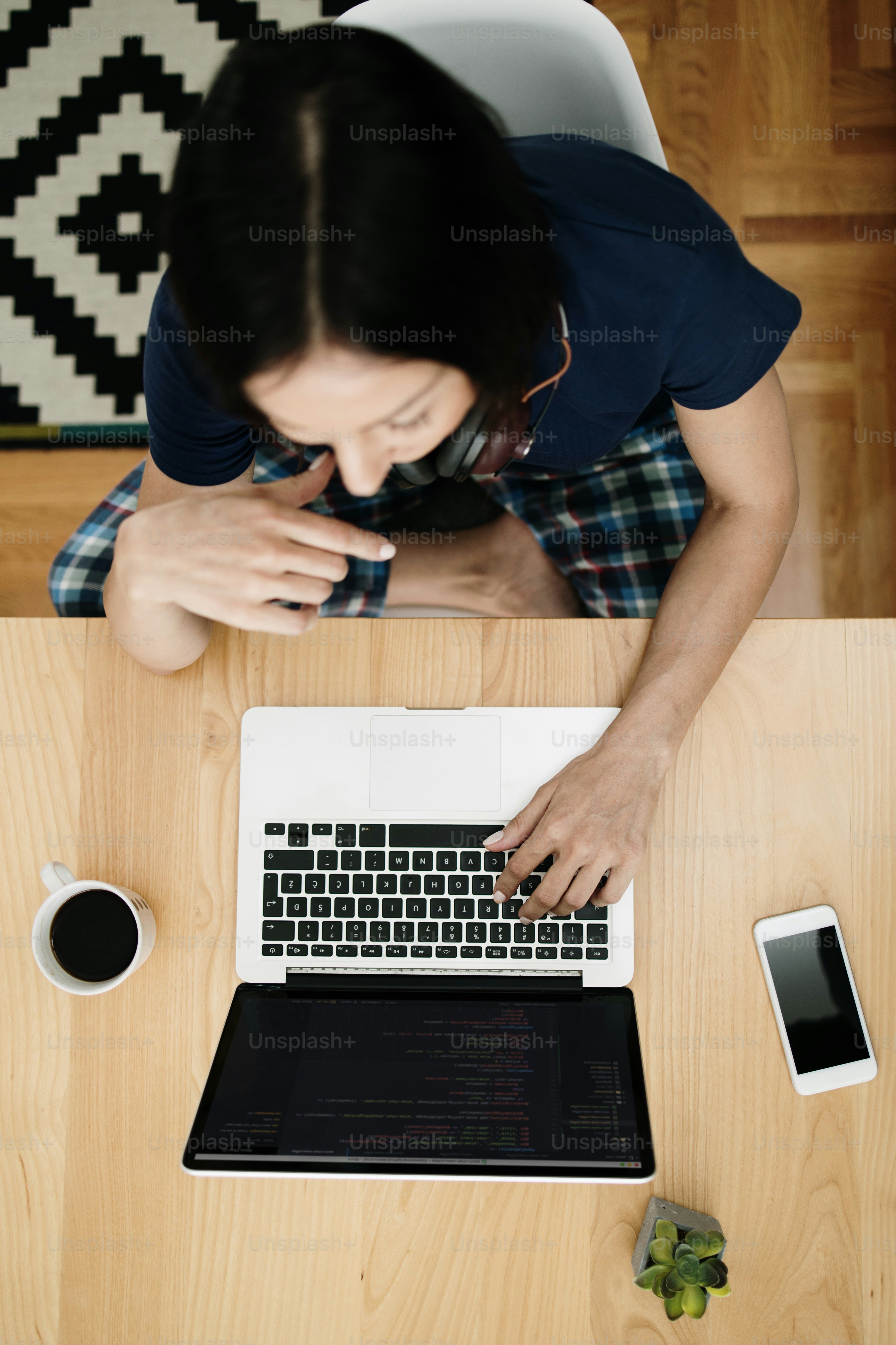 Attractive and happy middle age female freelancer is working at her home. She is using headphones, listening to music and singing. Modern kitchen in background. Freelancing job concept.