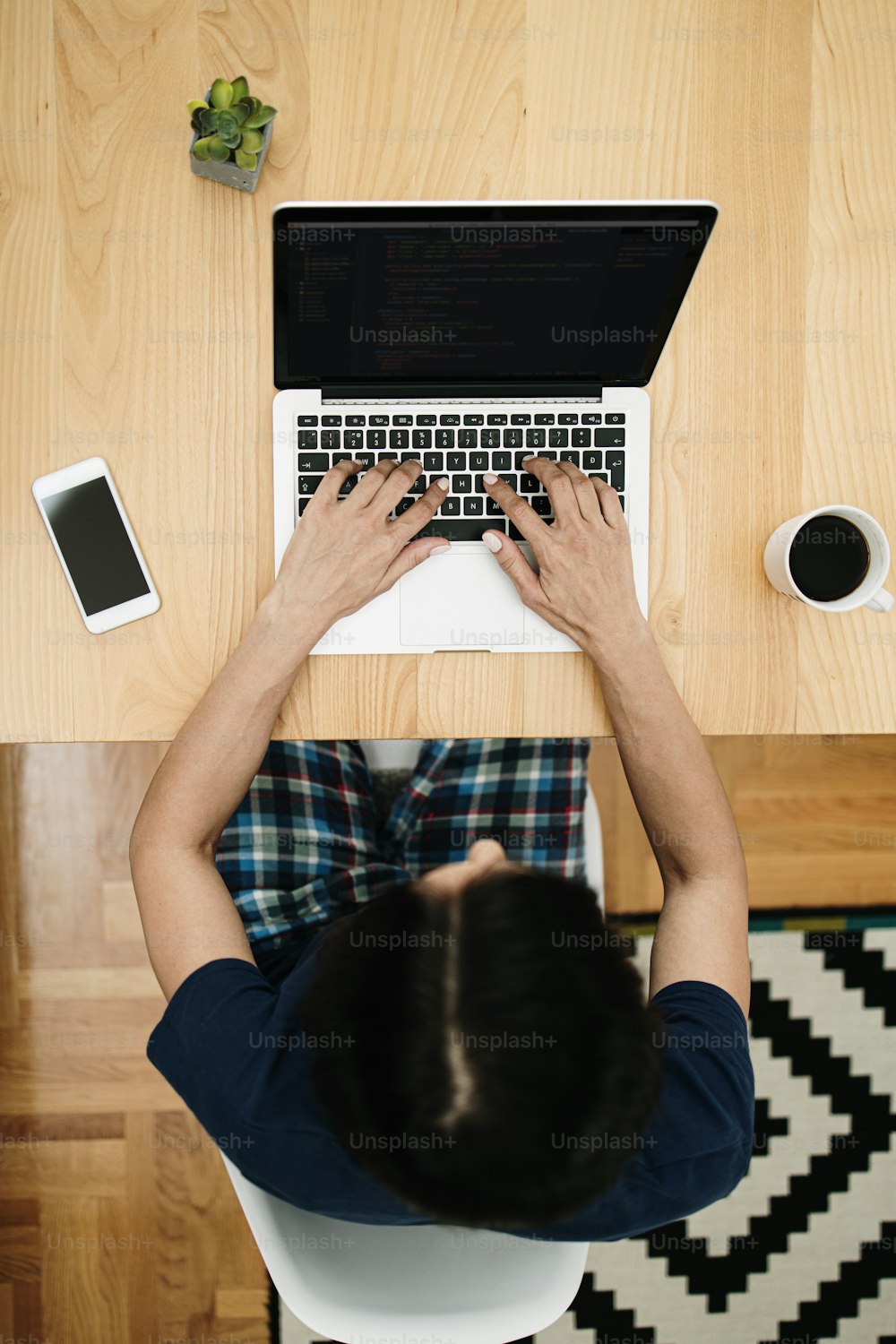 Attractive and happy middle age female freelancer is working at her home. She is using headphones, listening to music and singing. Modern kitchen in background. Freelancing job concept.