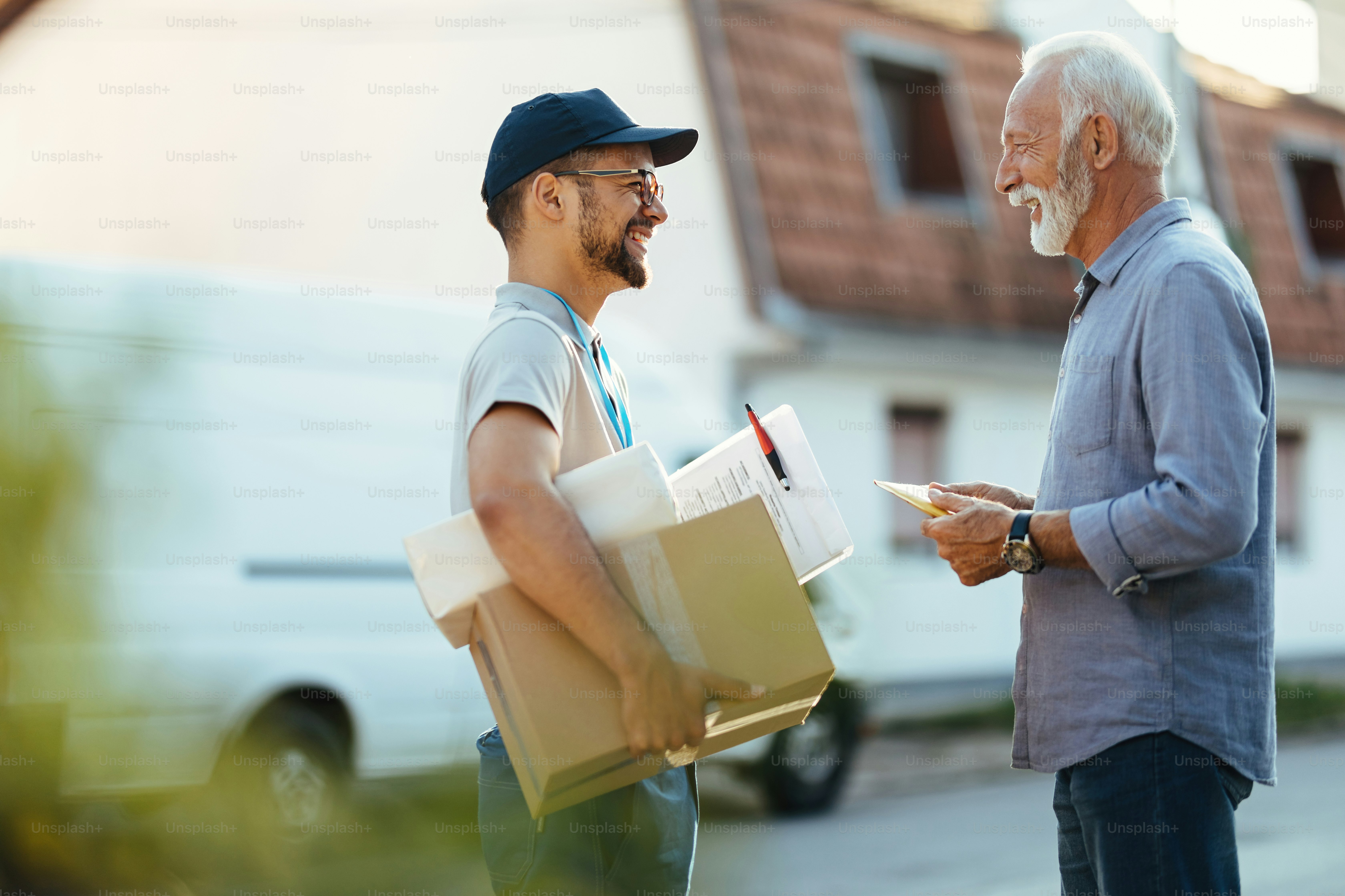 Happy senior man communicating with courier while receiving home delivery.