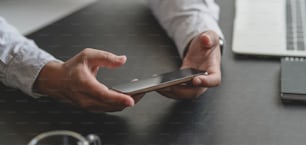 Close-up view of businessman looking for information on smartphone in his dark modern workspace