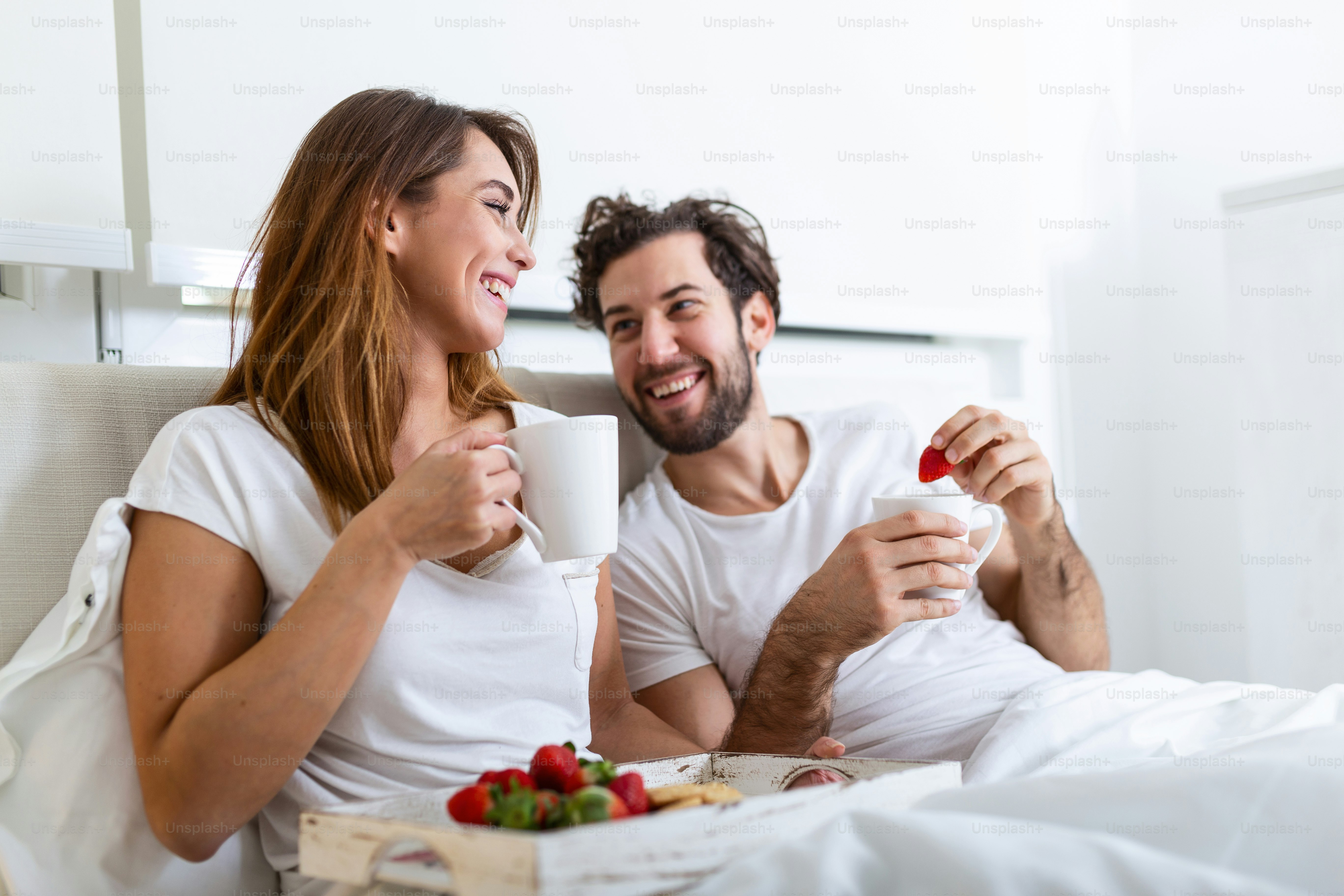 Foto zum Thema Junges verliebtes Ehepaar frühstückt in ihrem Bett