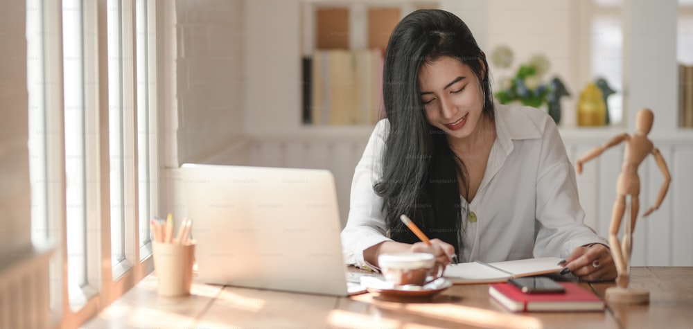 Ausschnittaufnahme einer jungen professionellen Geschäftsfrau, die an ihrem Projekt mit Laptop in einem modernen Büroraum arbeitet
