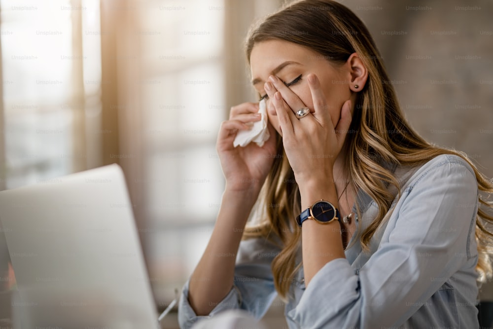 Giovane imprenditrice con il virus del raffreddore e dell'influenza che ha mal di testa mentre lavora in ufficio.