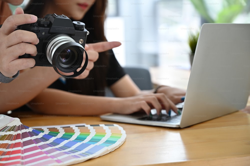 Fotografo e partner che lavorano con il computer portatile e il concetto di colorazione.