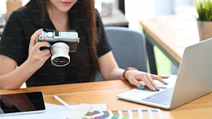 カメラとラップトップコンピュータで作業する若い創造的な女性。