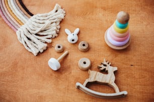 유아를 위한 친환경, 플라스틱 무료 교육 장난감. 나무 테이블에 아이를 위한 세련 된 나무 장난감입니다. 현대적인 다채로운 나무 피라미드는 반지와 마크라메 무지개를 분해합니다.
