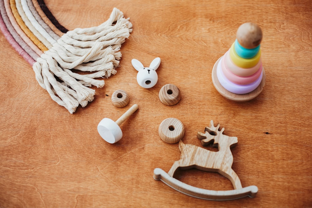 Giocattoli educativi ecologici e privi di plastica per il più piccolo. Eleganti giocattoli in legno per bambini su tavolo in legno. Moderna piramide in legno colorato con anelli smontabili e arcobaleno macramè.
