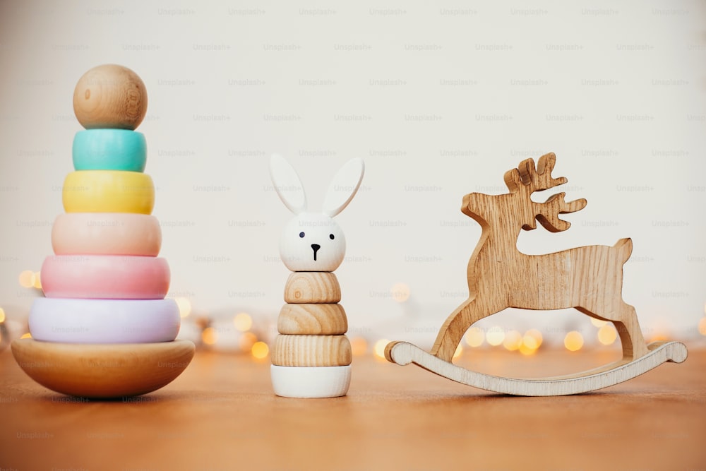 Cadeaux de Noël sans plastique respectueux de l’environnement pour les tout-petits. Jouets en bois élégants pour enfant sur table en bois. Pyramide en bois colorée moderne avec anneaux, lapin simple et renne.
