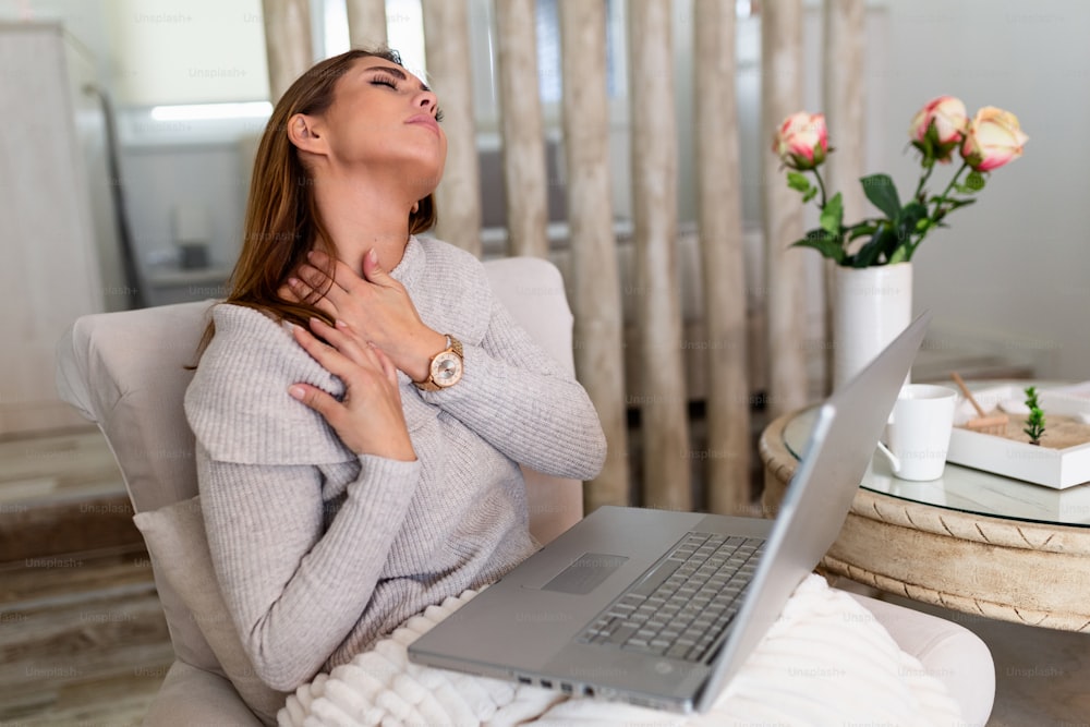 Femme d’affaires ressentant une douleur au cou après s’être assise à la table avec un ordinateur portable. Femme fatiguée souffrant du syndrome du bureau à cause de longues heures de travail à l’ordinateur. Jolie fille massant les muscles tendus de son cou