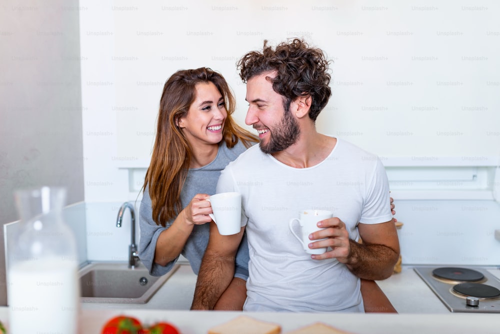 Romantic couple in love spending time together in kitchen. Cute young couple drinking coffee in kitchen and enjoying morning time together
