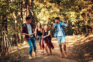 Group of four friends having fun hiking through forest together.