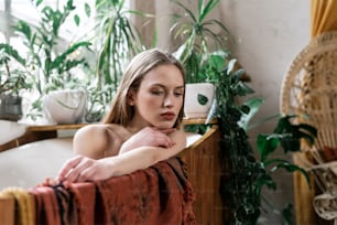Young adult girl resting and relaxing at home, enjoying spa procedure, lying in bathtub, taking bath in bathroom with green plants in flowerpots at cozy interior
