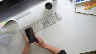 Espacio de trabajo de creatividad: Toma superior del teléfono inteligente en las manos.