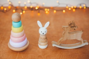 Eco friendly plastic free christmas gifts for toddler. Stylish wooden toys for child on wooden table. Modern colorful wooden pyramid with rings, wooden bunny and deer