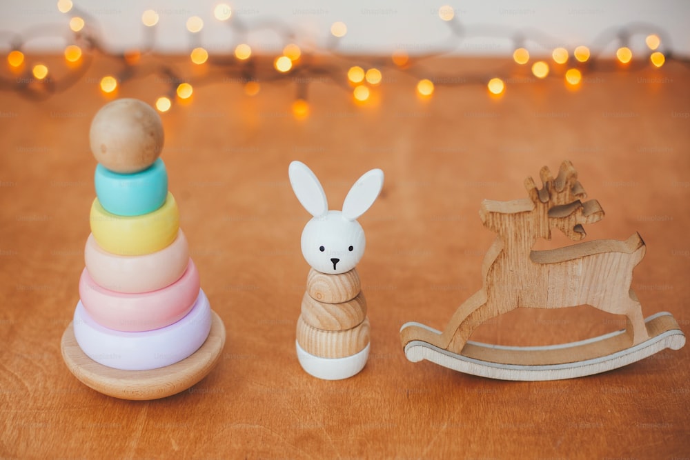 Umweltfreundliche plastikfreie Weihnachtsgeschenke für Kleinkinder. Stilvolles Holzspielzeug für Kinder auf Holztisch. Moderne bunte Holzpyramide mit Ringen, Holzhase und Hirsch