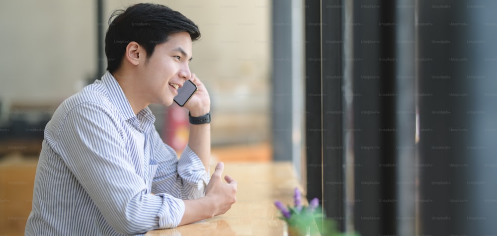 Young professional businessman speaking on the phone with his customer in modern office room