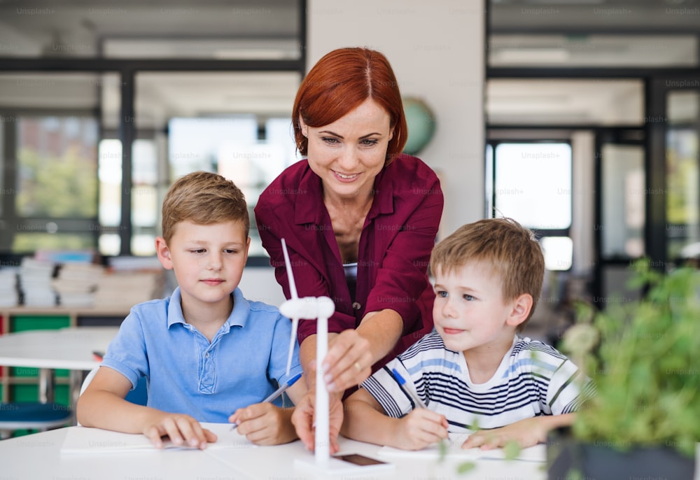 Un gruppo di bambini della piccola scuola con l'insegnante nella classe di scienze che imparano l'ambiente.