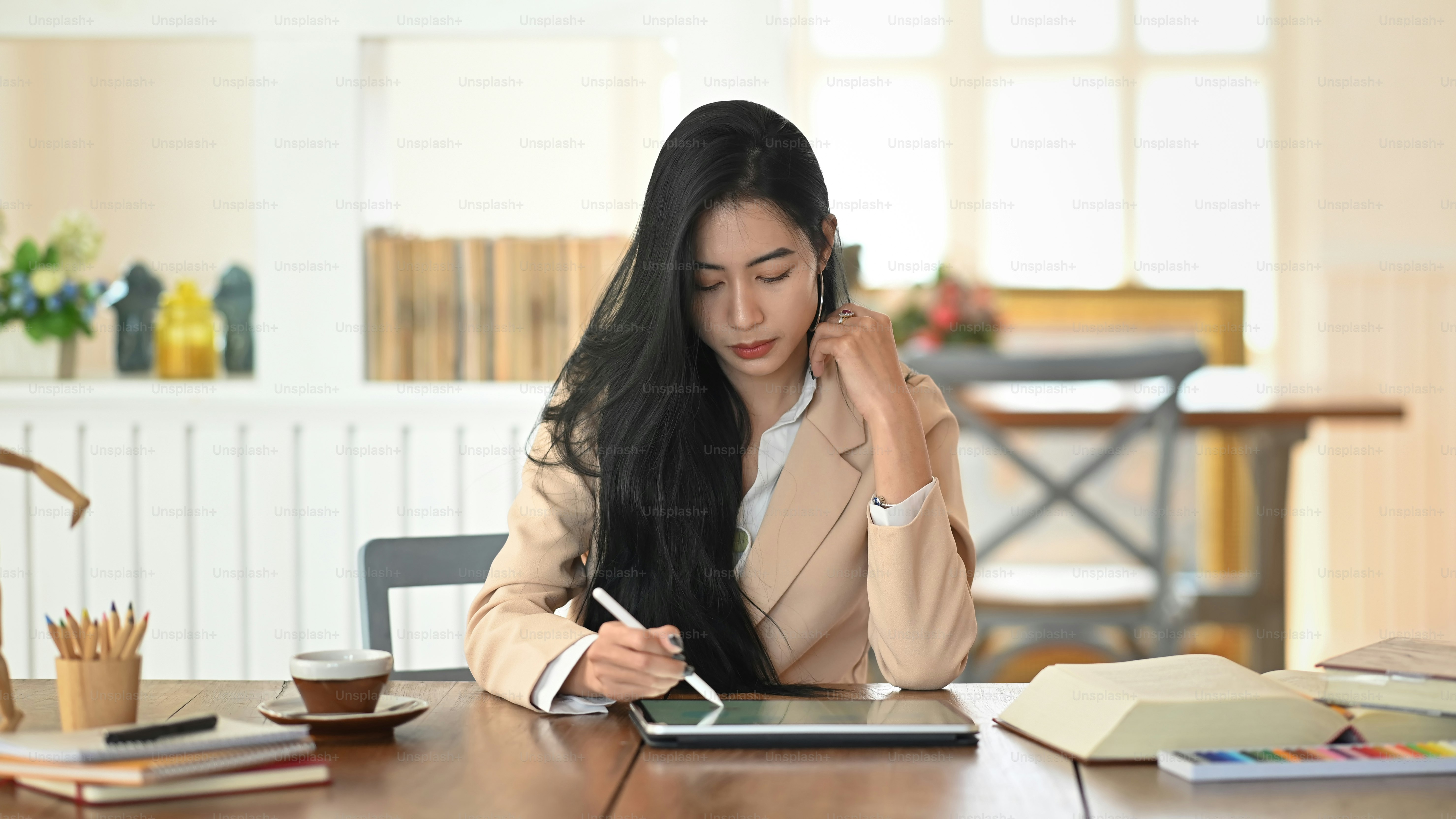 그녀의 태블릿과 스타일러스 펜을 사용하는 편집자 책.