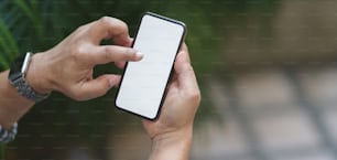 Close-up view of young professional businessman using mock up smartphone with outdoor office background