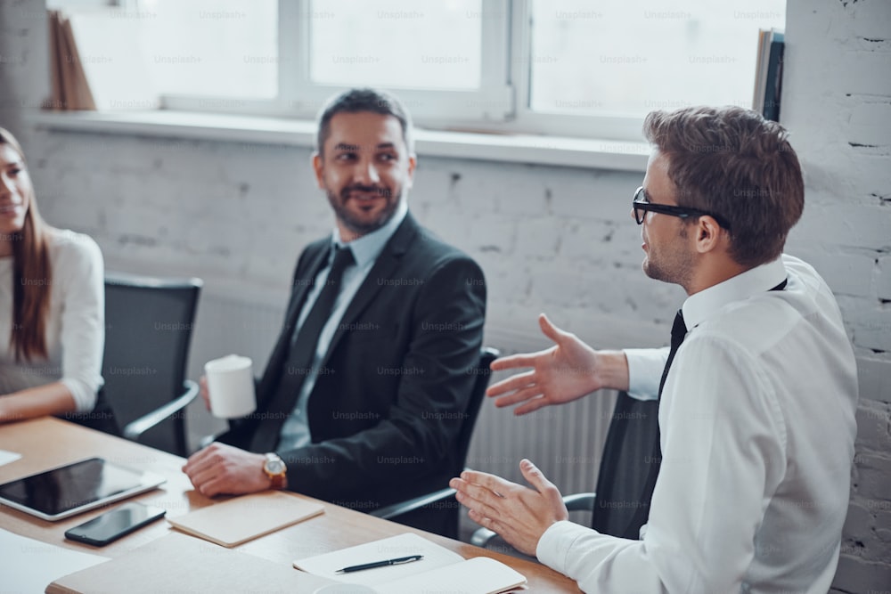 Happy businessmen discussing something and smiling while working together in the office