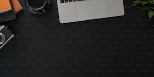 Foto aérea do local de trabalho elegante escuro com laptop e suprimentos de escritório no fundo preto da mesa