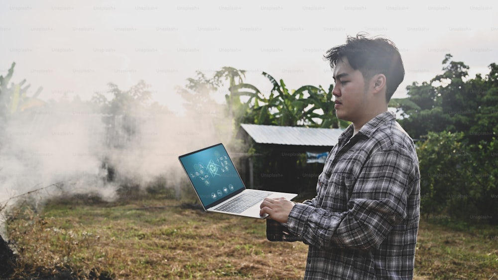 Agriculture technology concept, man with laptop standing on agriculture field.