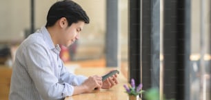 Portrait of young businessman using his smartphone in modern workplace