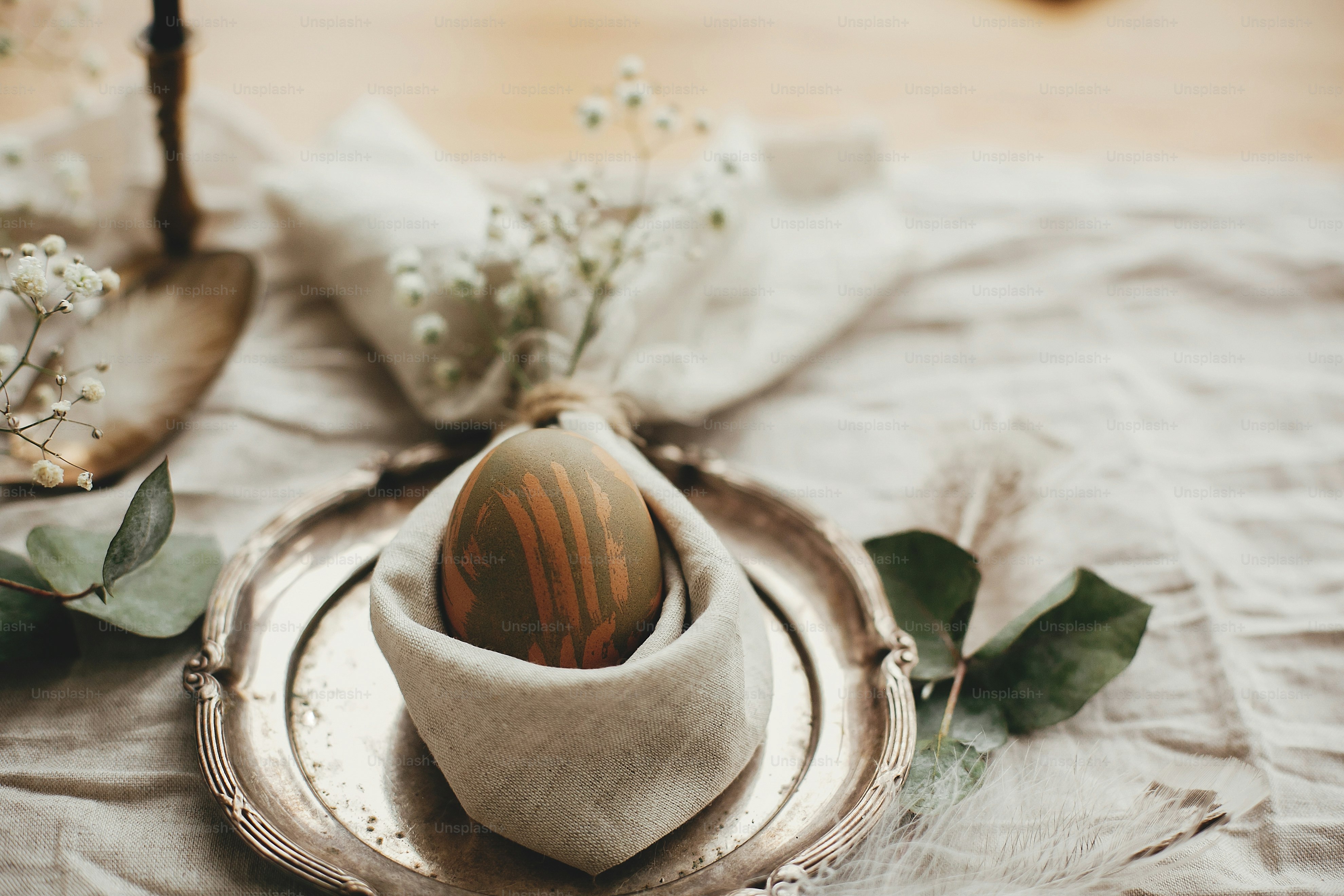Decoraciones rústicas de mesa de Pascua. Elegante mesa de brunch de Pascua  con huevo en servilleta de conejito de Pascua. Huevo verde teñido natural  moderno en servilleta con orejas de conejo, flores, image size:3000x2000