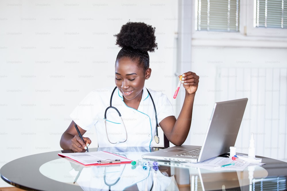 Female doctor in white coat holding blood test tubes in hands while wrapped up in work at modern lab. Female life science professional holding glass cuvette. Healthcare and biotechnology concept.