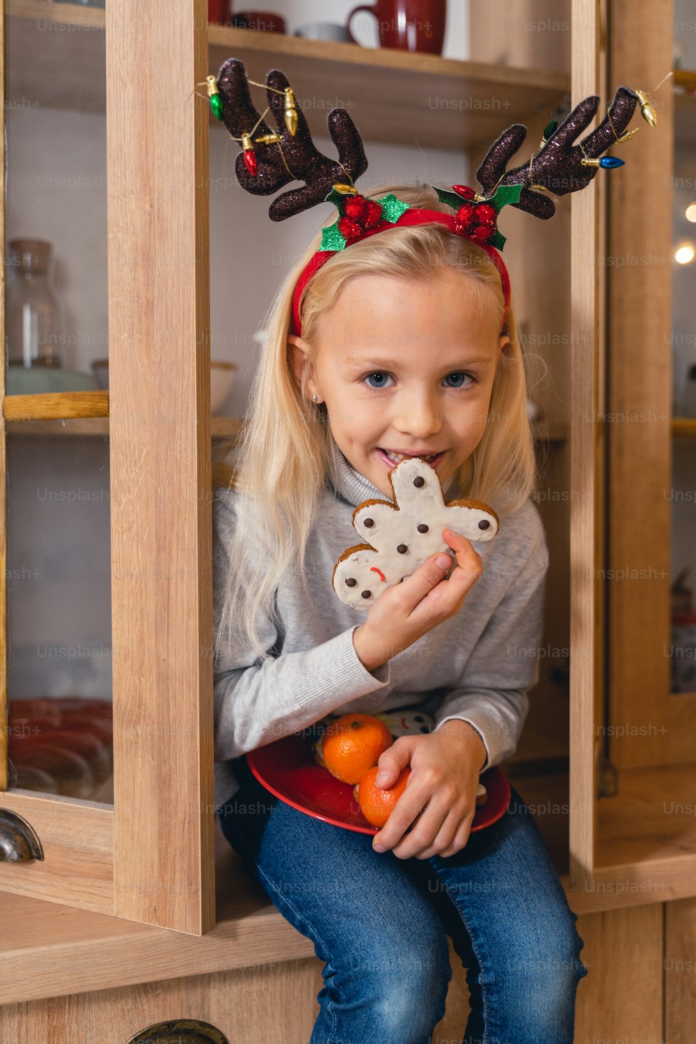 Pretty little girl eating a gingerbread man in the kitchen