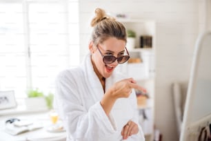A young woman with sunglasses indoors at home in the morning, having fun.