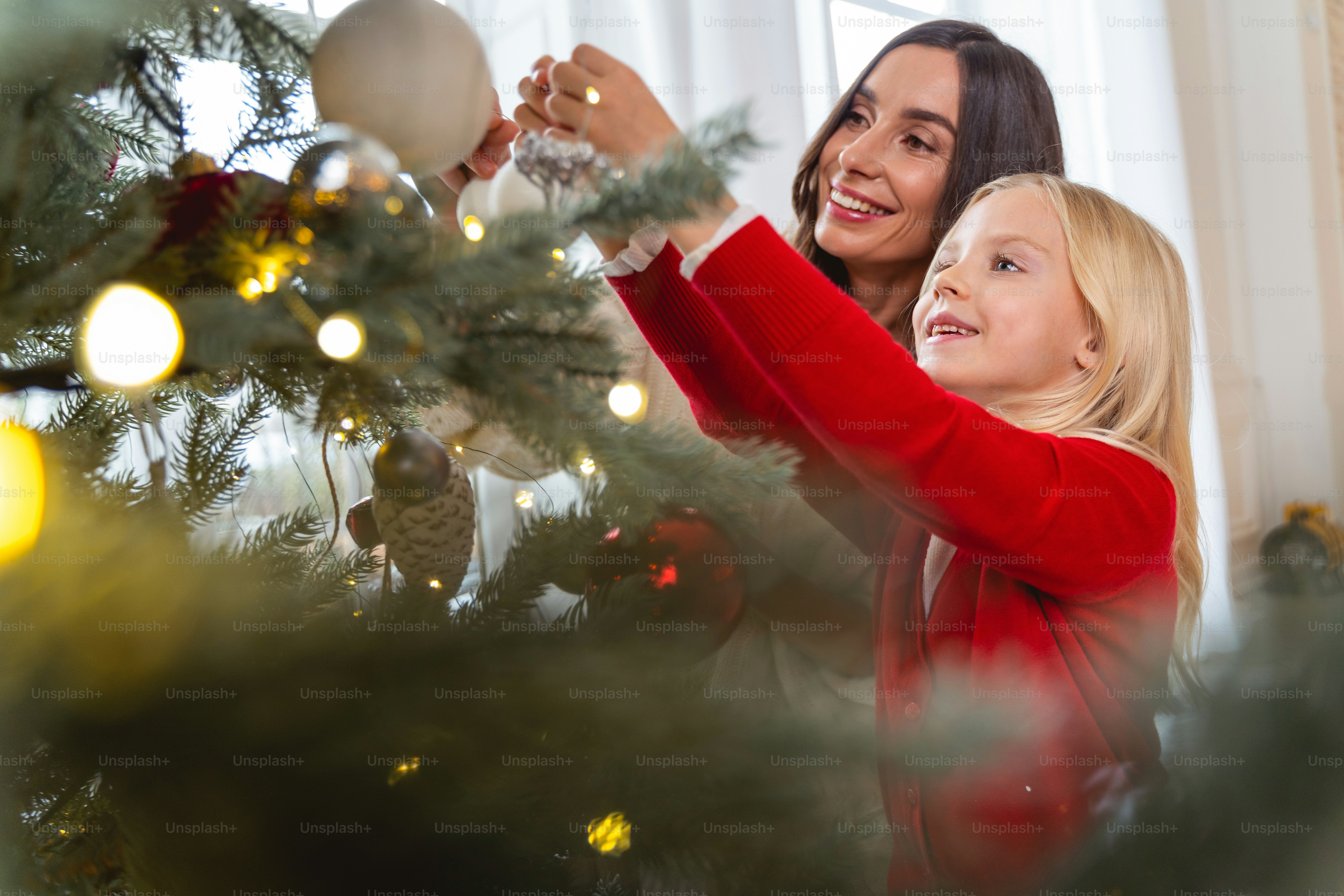 Adorable girl and her beautiful mother holding the Christmas tree balls