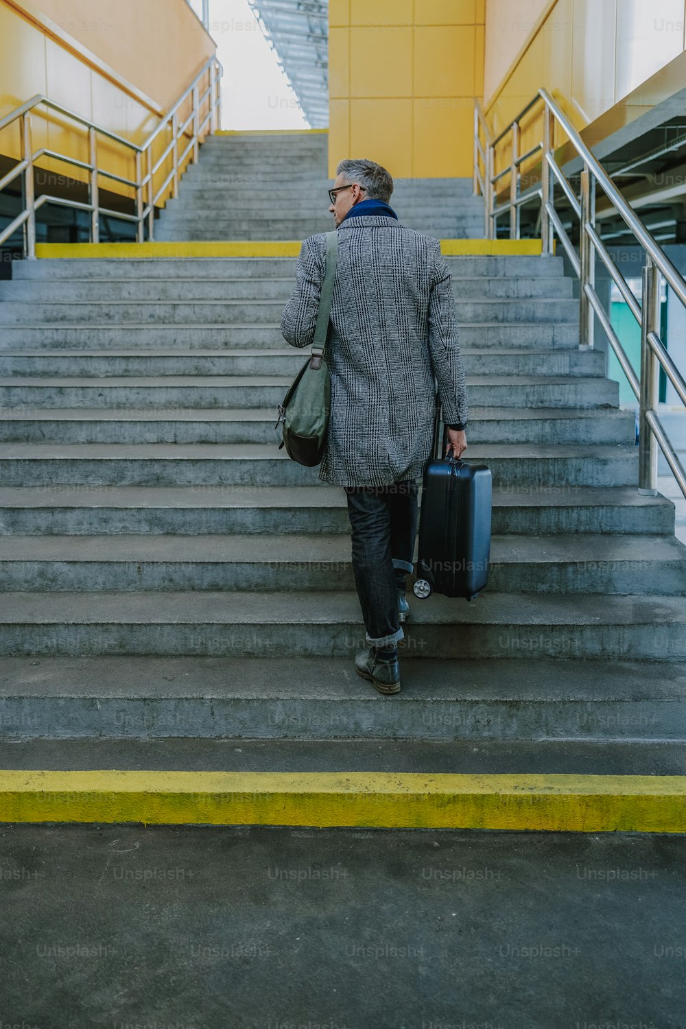Stylish gentleman holding trolley bag and climbing up the stairs stock photo
