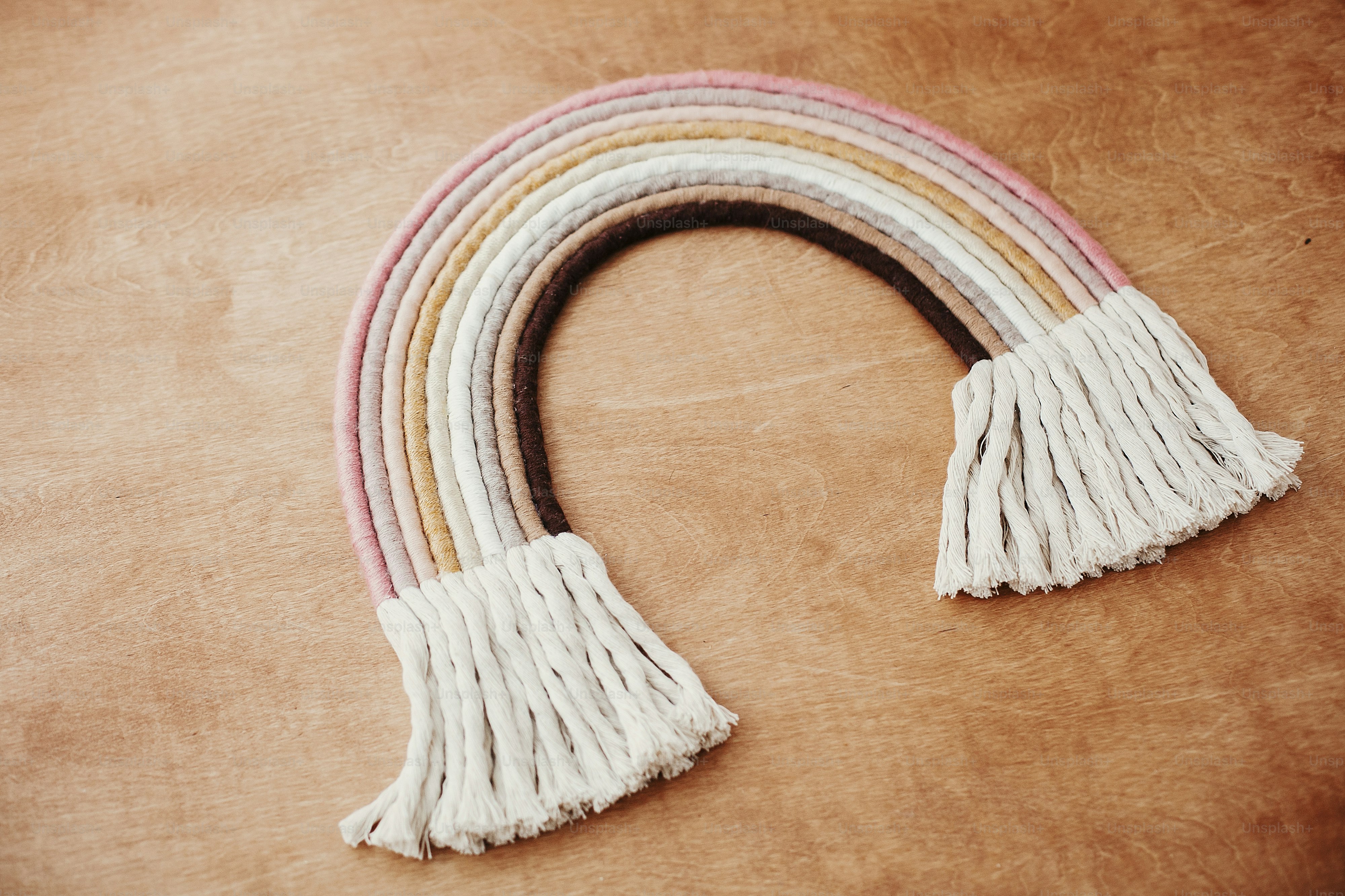 Decoração elegante do arco-íris de macramê na mesa de madeira. Arco-íris de corda boho moderno para quarto de bebê ou quarto de menina elegante simples. Decoração de macramê pendurada na parede